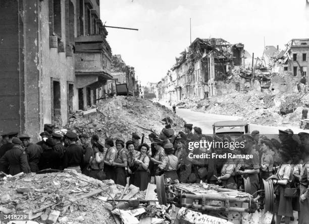 Allied soldiers queuing outside the devastated German Chancellery to see the remains of Adolf Hitler's underground shelter where he is reputed to...