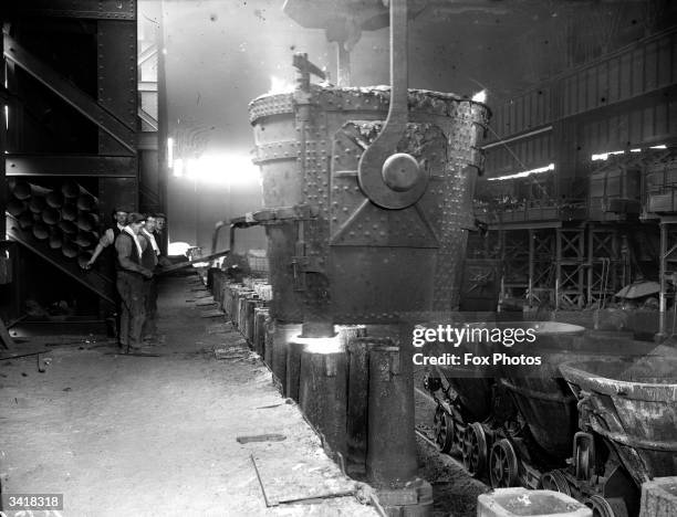 Workmen in a steel mill pouring molten steel into an ingot mould.