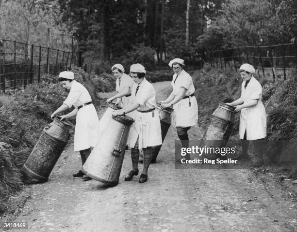 Students from the Studley Agricultural College in Warwickshire rolling milk churns across a lane.