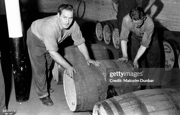 Workers rolling barrels of whisky along the floor at Johnnie Walker's distillery in the Scottish industrial town of Kilmarnock. The Johnnie Walker...