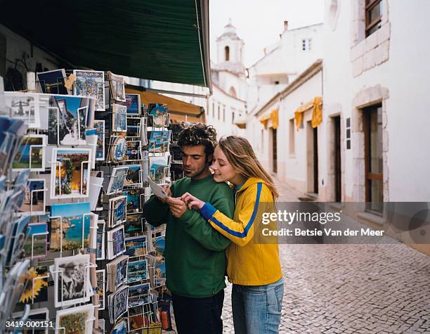 couple looking at postcards - souvenir stock-fotos und bilder