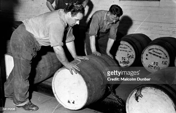 Workers rolling barrels of whisky along the floor at Johnnie Walker's distillery in the Scottish industrial town of Kilmarnock. The Johnnie Walker...
