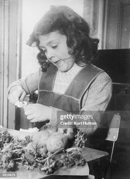 Sorel Waddington preparing turnips at the Fortis Green nursery school. The United Nations Organisation, Organised children of different nations to...