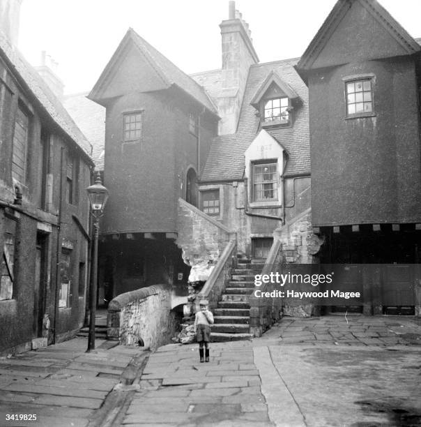 Small boy looks up at a 17th-century building, which used to be an inn, in White Horse Close in the old town area of Edinburgh. Edinburgh has a long...