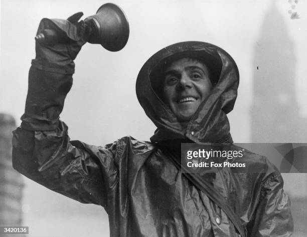 An air raid warden ringing a bell to signal the 'All Clear' after a gas raid.