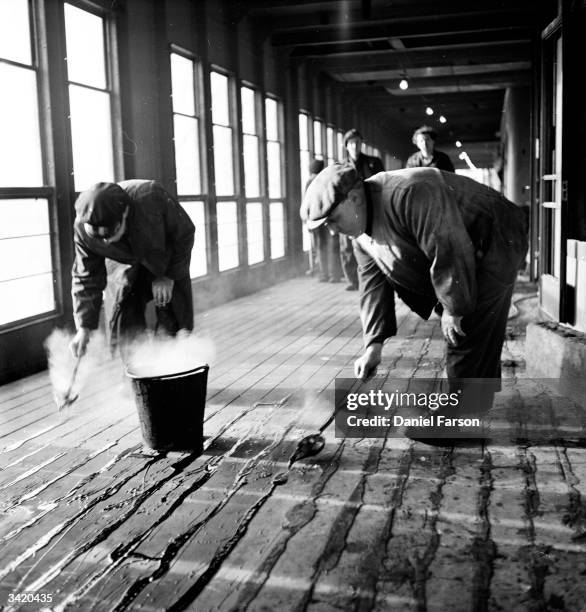 Workmen filling the cracks in the deck of the British India Company passenger liner 'Uganda' with tar, in Clydeside docks. The ship, built for...