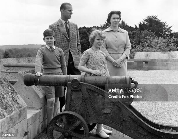 Queen Elizabeth II and Prince Philip, Duke of Edinburgh with their children Charles, Prince of Wales and Princess Anne, by a cannon of a bygone age...