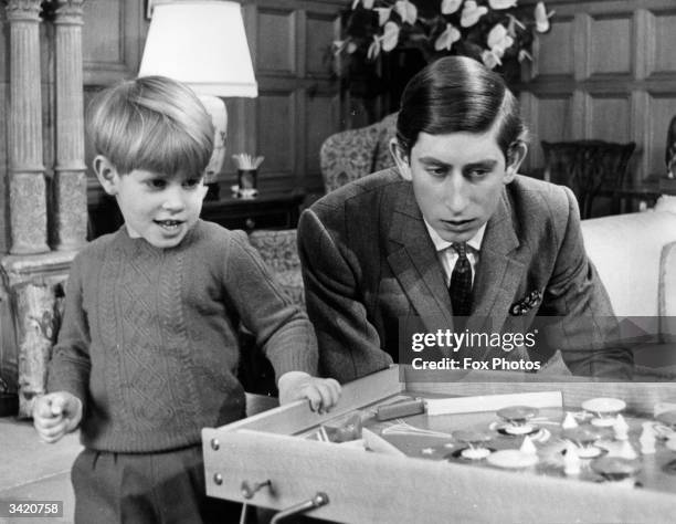 Prince Charles looks on as his five year old brother Prince Edward enjoys a game of bagatelle at Sandringham House, Norfolk.