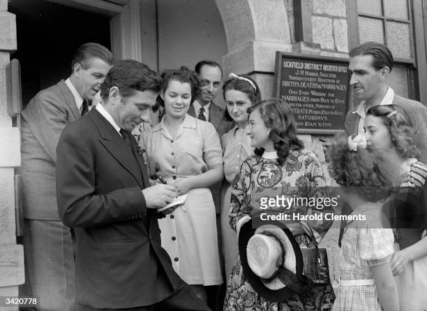 English actor Robert Newton signing autographs outside the registry office where he married Nathalie Newhouse.