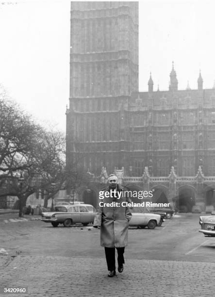 Harold Wilson outside the Houses of Parliament, London, in the year he succeeded Hugh Gaitskell as leader of the Labour party. He is wearing a Gannex...