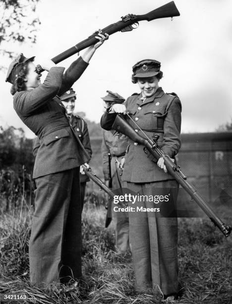 Girls cleaning their rifles at the Miniature Rifle Club, at a West Country Transport depot. The rifles are service weapons adapted for small bore...