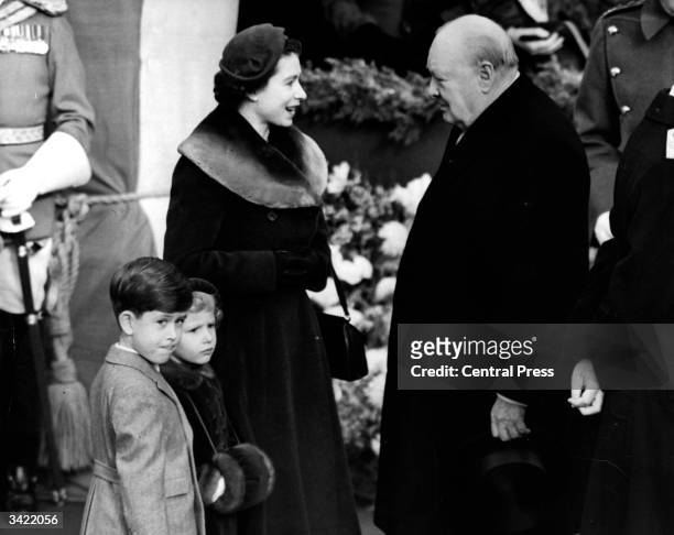 Elizabeth II, Queen of England with Prince Charles and Princess Anne chatting to Sir Winston Churchill .