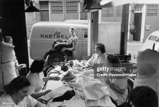 Women working in Norman Hartnell's salon watch as the Queen's coronation dress is taken for delivery to Buckingham Palace. Original Publication:...