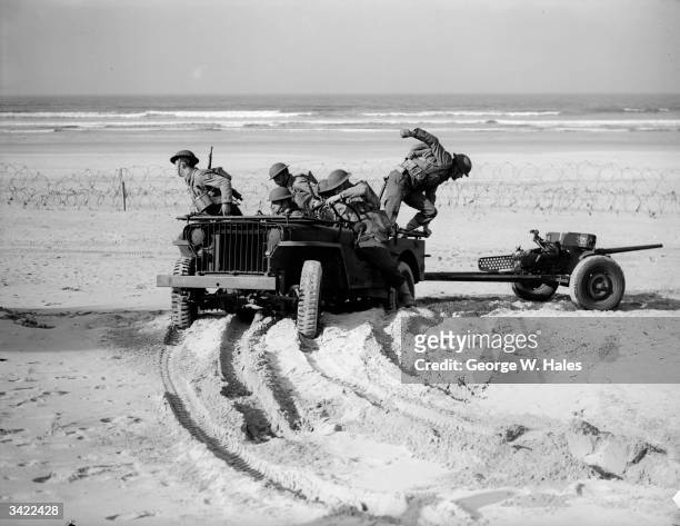 Army troops stationed in Northern Ireland hauling an anti-tank gun behind a jeep during exercises along the Irish coast.