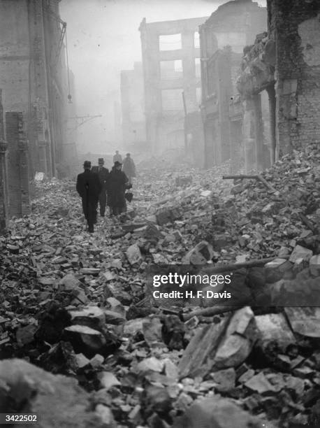 City workers picking their way through the rubble and debris of Fore Street in the City of London destroyed by incendiary bombs during the Blitz.