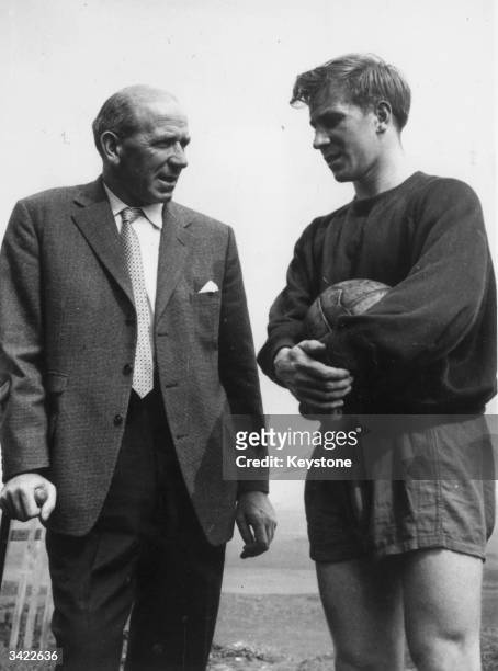 Manchester United Football Club manager Matt Busby, left, talking to team member Bobby Charlton. Busby was only recently back in the country after...