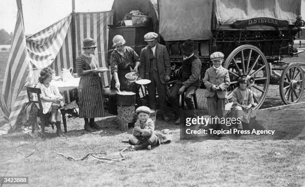 Gypsy family at an Ascot race meeting enjoy a meal outside their caravan.