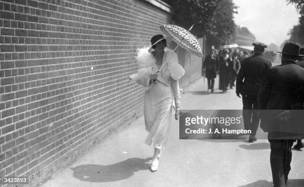 Using a parasol to shelter from the sun, on the third day of the races at Ascot.