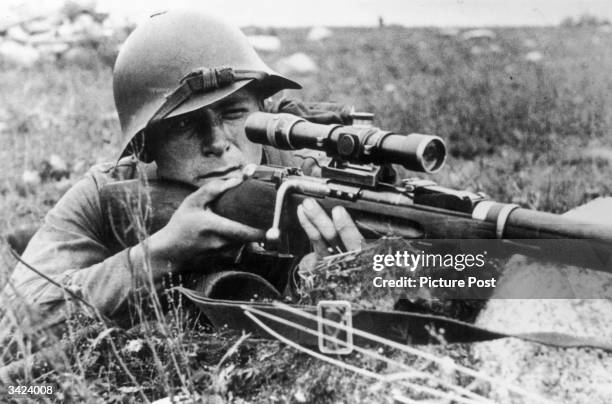 Soviet sniper targets the enemy with the telescopic sight on his rifle.