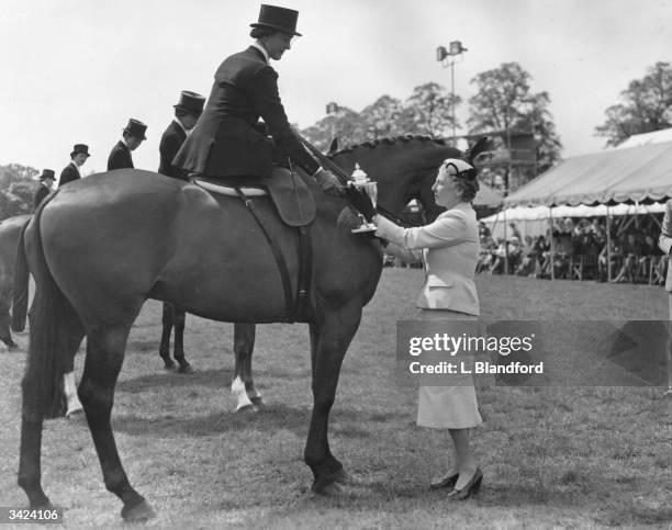 Lady Abel Smith presenting the Late Majesty King George VI Cup to Miss Ann Davey on Earmark, winner of the Ladies Hunter Class and Middleweight...