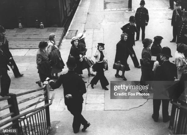 Germans and Austrians leaving mainland Britain for an interment camp on the Isle of Man, arriving at the station escorted by police.