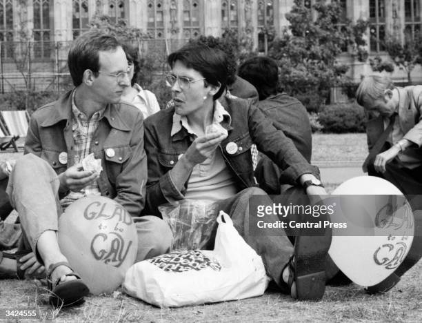 Gay men picnic in Victoria Gardens by the Houses of Parliament, London, during 'Gay Pride Week'. Their balloons have the slogan 'Glad to be Gay'.
