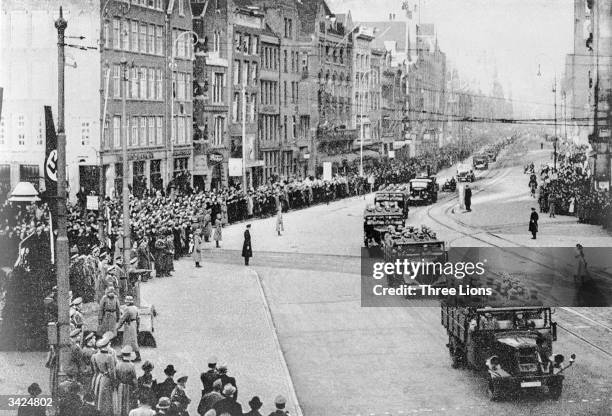 Nazi troops and armoured divisions driving along a main street in Amsterdam, on a route from Central Station past the Queen's Palace.