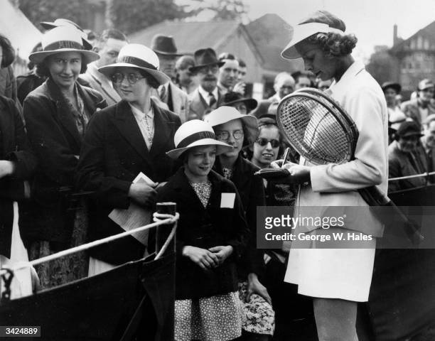 American tennis player Alice Marble signing autographs for young fans at the Surrey Grass Courts Championships in Surbiton.