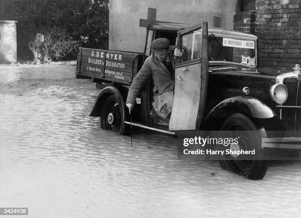 Van driver measuring the depth of the water before deciding whether or not to drive through the sea water that has flooded a street in Seaford, near...