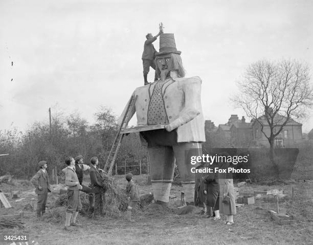 Mr C W Clarke putting a rocket on the hat of his 23ft Guy Fawkes which weighs 3 tons, watched by villagers in Beckenham.