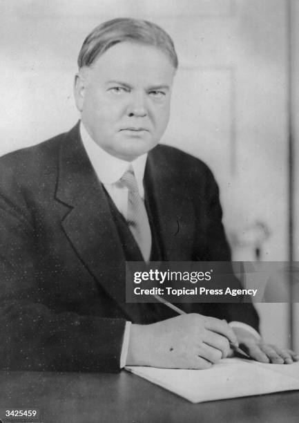 Herbert Hoover , later the 31st President of the United States, seated at a desk writing.