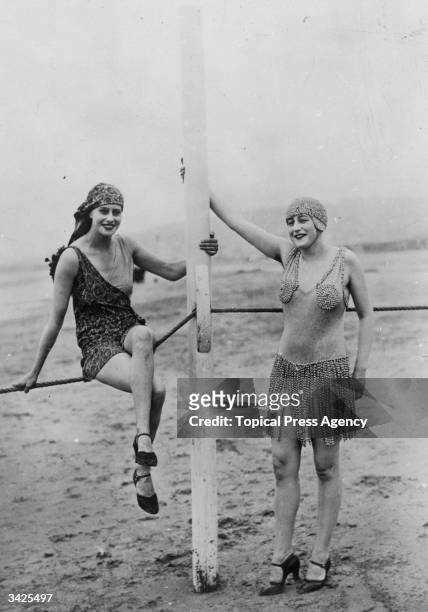 Two women modelling bathing suits on the beach at Deauville.