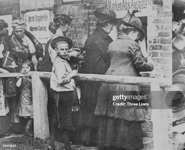 German housewives queue for new ration books, as the effects of the Allied blockade are felt on the German home front.