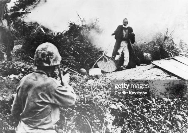 Japanese emerges from hiding to surrender to an American soldier.