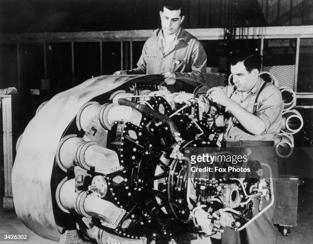 Technicians in a General Electric Company plant in New York state working on a turbo jet airplane engine for a P-59A propellerless fighter plane.