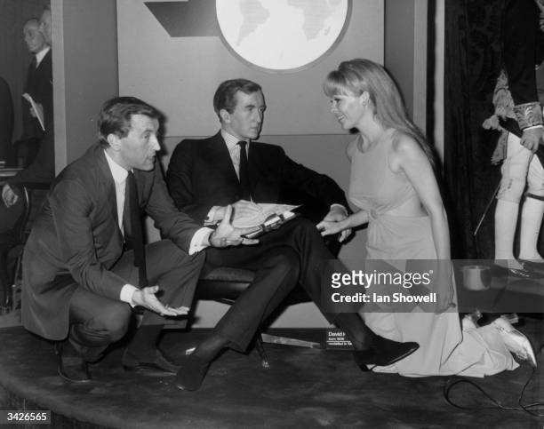 English television journalist David Frost chats with Judith Arthy, a member of the cast of 'The Secretary Bird', alongside a wax work effigy of...