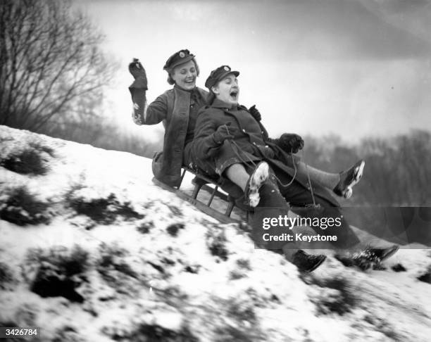 Two ATS girls enjoying the snow on their toboggan at a gun site in London.