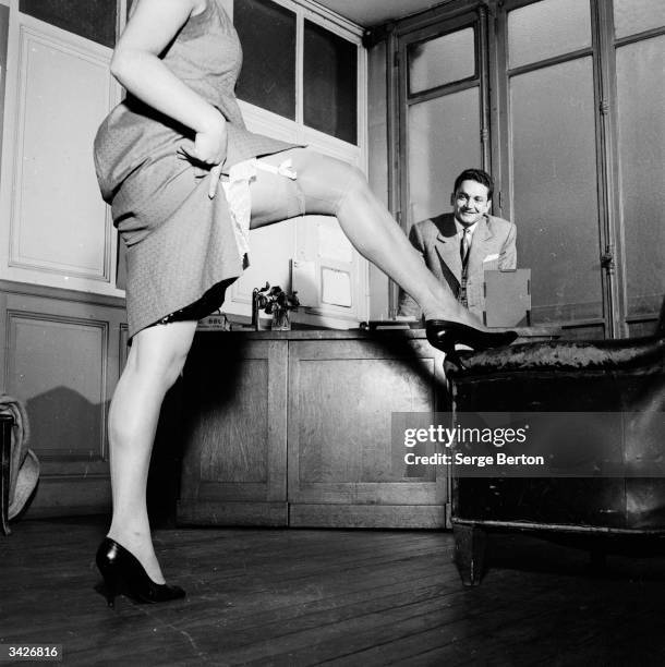 Year old salesgirl Patricia Rok 'shows a leg' for Mr Diaz during an interview to enter a competition for amateur strippers at the 'Nouveau Cabaret du...