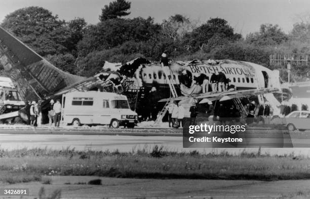 Firemen examine the burnt out wreckage of a Boeing 737 passenger airliner bound for Corfu, which exploded during take-off at Manchester Airport. 54...