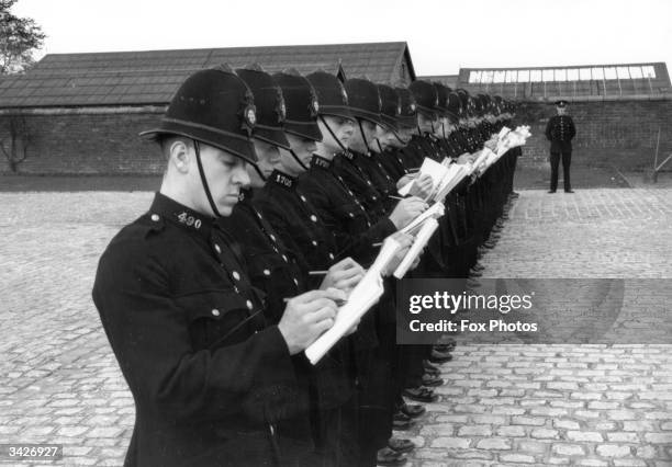 Recruits of the Lancashire Constabulary, being trained at Stanley Grange, Houghton, near Preston, take notes during a staged smash and grab raid, as...