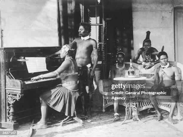 Zulu woman playing the piano while a group of others sit and listen.