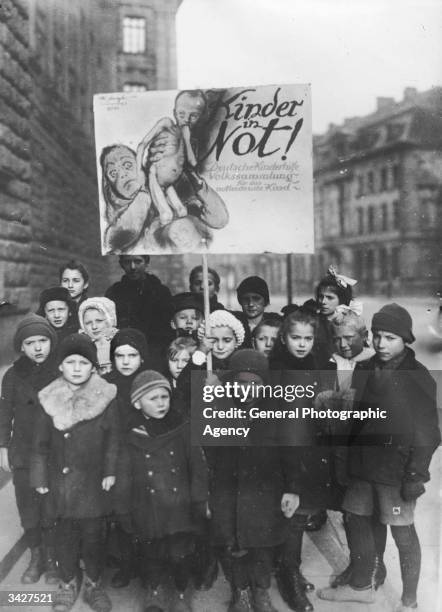 Group of German children holding up a sign which reads 'Children in Need!' in an attempt to collect charitable contributions for Germany's destitute...