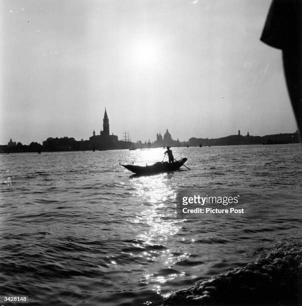Lone gondolier silhouetted against the dawn as it breaks over the Grand Canal in Venice. Original Publication: Picture Post - 5402 - Venice Party -...