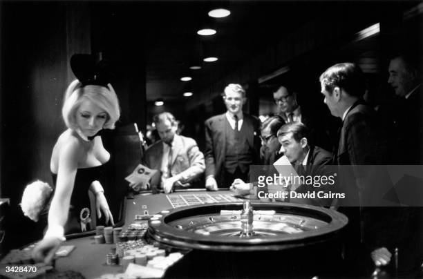 Bunny girl croupier at the Playboy club supervises a roulette wheel.