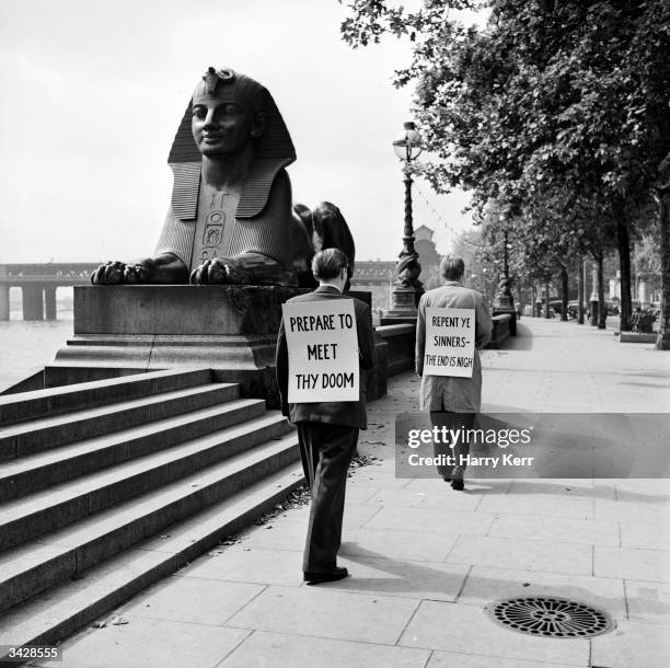 Sandwich-board men beside the Victorian sphinxes by George Vulliamy at Cleopatra's Needle on the Embankment in London.