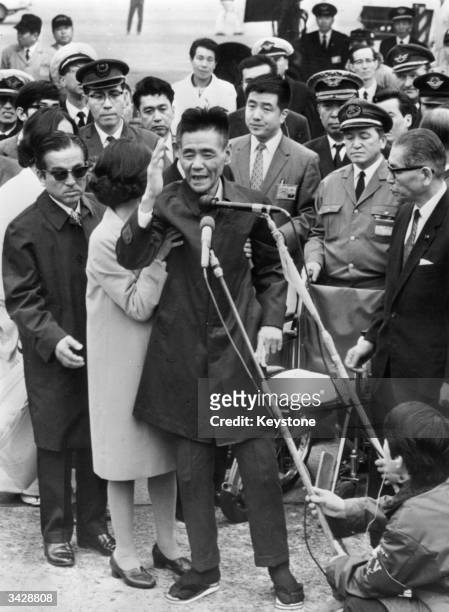 Shoichi Yokoi, a former sergeant in the Imperial Japanese Army, is helped to stand by a nurse as he acknowledges the cheers of the crowd at Tokyo...