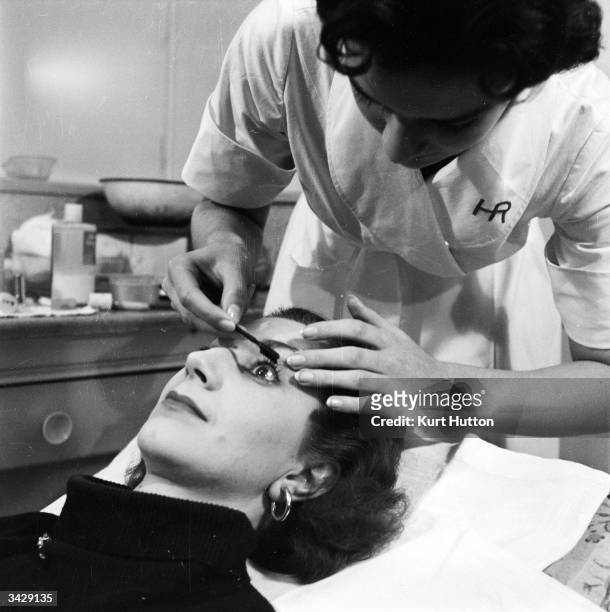 British actress Moyra Fraser is given an application of mascara by a beautician at one of the salons of Polish-born US businesswoman Helena...
