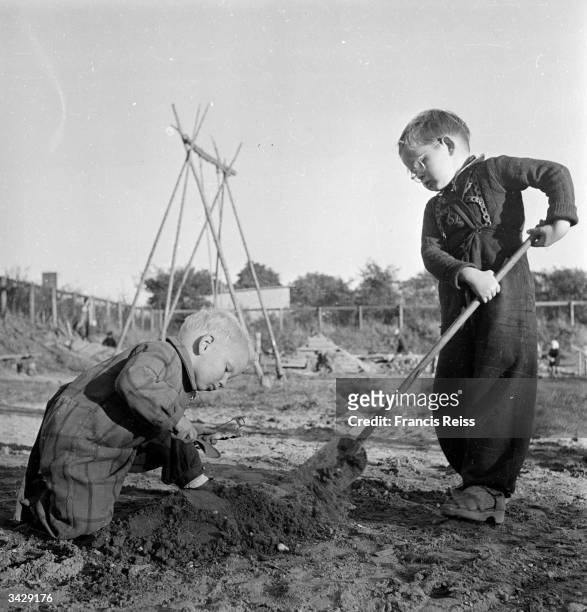 Young children helping each other to build mud castles in the experimental playground allotted to them on an abandoned wasteground in Emdrup,...