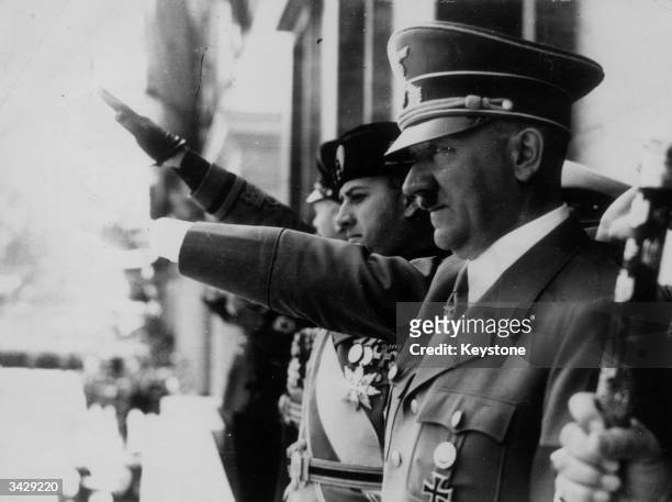Adolf Hitler gives the fascist salute at a parade during WW II. Visible on the balcony with him are Galeazzo Ciano and Italian Benito Mussolini ....