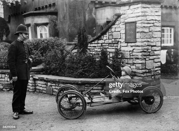 Policeman wonders whether to book Basil Sanderson, England's youngest motorist as he drives his vehicle out of the Selsdon Park Hotel.